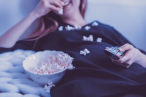 kobieta oglądająca film i jedząca popcorn